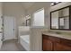 Bathroom featuring a soaking tub with tile surround, dark wood cabinets, and a large mirror at 6370 Stillwood Ln, Cumming, GA 30041