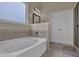 Bright bathroom featuring a soaking tub, neutral tile, and white cabinets at 6370 Stillwood Ln, Cumming, GA 30041