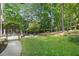Lush backyard featuring a concrete path, mature trees, manicured lawn, and an elaborate trellis in a landscaped garden at 120 Forest Breeze Cv, Alpharetta, GA 30022