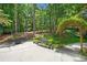 Backyard featuring a concrete patio, a seating area, mature trees, and an elaborate trellis in a landscaped garden at 120 Forest Breeze Cv, Alpharetta, GA 30022