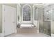 Luxurious bathroom with a soaking tub, glass-enclosed shower, and a large window offering wooded views at 120 Forest Breeze Cv, Alpharetta, GA 30022