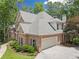 Side view of a two-story brick home with a manicured lawn, mature trees, side-entry garage, and well-maintained landscaping at 120 Forest Breeze Cv, Alpharetta, GA 30022