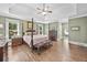 Spacious main bedroom featuring a tray ceiling, hardwood floors, and elegant four-poster bed with matching bench at 120 Forest Breeze Cv, Alpharetta, GA 30022