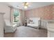 Bedroom with decorative wallpaper, a crib, and a comfortable chair, creating a cozy space at 1055 Beacon Hill Xing, Alpharetta, GA 30005
