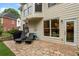 A stone patio with lounge chairs, grill, and access to the home's interior through a glass door at 1055 Beacon Hill Xing, Alpharetta, GA 30005