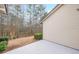 View of back patio and side of house showcasing neutral siding, a gray patio, and view of wooded area at 3916 Abbott Way # 2, Powder Springs, GA 30127