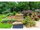 Backyard landscaping showcases vibrant plants, flowers, stone steps, and a cozy seating area surrounded by lush greenery at 2263 Hill Creek Way, Marietta, GA 30062