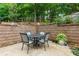 Outdoor patio area with dining set, surrounded by a retaining wall and lush greenery at 2263 Hill Creek Way, Marietta, GA 30062