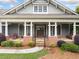 Inviting front porch with brick accents, columns, seating, and a beautifully landscaped garden at 3157 Perimeter Cir, Buford, GA 30519