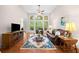 Bright living room with soaring windows, hardwood floors, ceiling fan, and a decorative area rug at 3157 Perimeter Cir, Buford, GA 30519