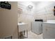 Laundry room with a utility sink, washer, dryer, white wire shelving, and neutral walls at 4651 Oakleigh Manor Dr, Powder Springs, GA 30127