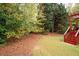 Tree line surrounds the yard with well maintained lawn and pine straw ground cover at 4651 Oakleigh Manor Dr, Powder Springs, GA 30127