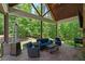 Cozy covered back patio with a stone fireplace, TV, comfortable seating, and scenic views at 193 Stonegate Trl, Carrollton, GA 30116