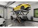 A car lift elevates a yellow sports car over a white SUV inside a modern garage at 193 Stonegate Trl, Carrollton, GA 30116