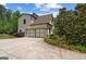 Home featuring a paved driveway leading to an attached three-car garage, set amidst lush greenery at 193 Stonegate Trl, Carrollton, GA 30116