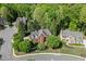 Aerial view of a red brick home with lush landscaping, surrounded by mature trees at 3284 Bakers Mill Ct, Dacula, GA 30019
