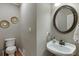 Powder room with hardwood floors, modern lighting, a decorative mirror, and a stylish pedestal sink at 3284 Bakers Mill Ct, Dacula, GA 30019