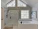 Bright bathroom featuring a glass shower, soaking tub, and decorative windows at 3284 Bakers Mill Ct, Dacula, GA 30019