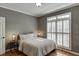 Comfortable bedroom featuring hardwood floors, soft lighting, and a large window with wooden shutters at 3284 Bakers Mill Ct, Dacula, GA 30019