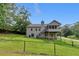 The back exterior of the house has a large fenced backyard with lots of beautiful green foliage at 3792 Refinement Way, Douglasville, GA 30135