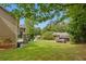 View of the backyard and side of the house, with a green lawn and mature trees at 3792 Refinement Way, Douglasville, GA 30135
