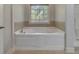 Bathroom featuring tiled whirlpool tub with window view at 3792 Refinement Way, Douglasville, GA 30135