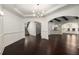 Open living space with dark wood floors, modern lighting, and arched doorways leading to kitchen and staircase at 625 Society St, Alpharetta, GA 30022