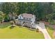 Two-story house with a covered front porch, featuring a well-manicured lawn, mature trees, and a long driveway at 226 Nacoochee Dr, Woodstock, GA 30188