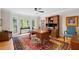 Bright home office with large bay windows, a dark wooden desk, hardwood floors, and colorful rug at 226 Nacoochee Dr, Woodstock, GA 30188