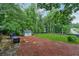 Spacious backyard featuring a stone patio, lush greenery, and a storage shed at 1206 Red Fox Cir, Woodstock, GA 30188