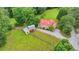 Aerial view of charming farmhouse with red roof and a barn, surrounded by green fields and mature trees at 1365 Lower Creighton Rd, Cumming, GA 30028