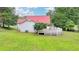 A country home featuring a large, white deck and a red metal roof sits on a grassy lot at 1365 Lower Creighton Rd, Cumming, GA 30028