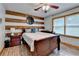 Bedroom with wood accent wall, dark furniture, ceiling fan, and wood-trimmed window at 1365 Lower Creighton Rd, Cumming, GA 30028
