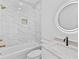 Elegant bathroom featuring marble tiling, a shower-tub combo, and a backlit round mirror at 157 Shadburn Ferry Rd, Buford, GA 30518