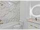 Elegant bathroom featuring marble tiling, a shower-tub combo, and a backlit round mirror at 157 Shadburn Ferry Rd, Buford, GA 30518
