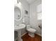 Elegant powder room featuring a pedestal sink, oval mirror, and a window with wooden floors at 3224 Wolf Club Sw Ln, Atlanta, GA 30349