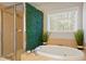 Bright bathroom featuring a glass shower and a soaking tub with tile flooring at 3224 Wolf Club Sw Ln, Atlanta, GA 30349