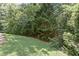 Well-kept backyard with green lawn, mature trees, and partial view of a wooden fence for added privacy at 931 Hidden Falls Se Ln, Smyrna, GA 30082