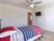 Bright bedroom featuring a ceiling fan, TV, and a bed with a red, white, and blue striped comforter at 3126 Cove View Ct, Dacula, GA 30019