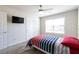 Bright bedroom featuring a TV, white walls, a ceiling fan, and a bed with a red, white, and blue comforter at 3126 Cove View Ct, Dacula, GA 30019