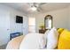 Bright bedroom with neutral walls, ceiling fan, TV, and a bed with yellow throw pillows and a floral comforter at 3126 Cove View Ct, Dacula, GA 30019