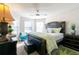 Main bedroom featuring a large bed, bedside table, bay windows, ceiling fan, and a turquoise side chair at 3126 Cove View Ct, Dacula, GA 30019