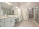 The modern bathroom features dual vanities, a glass shower, and a door leading to the walk-in closet at 300 Windsor Chase Trl, Johns Creek, GA 30097
