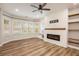 Living room with bay windows, ceiling fan, electric fireplace, and floating shelves at 300 Windsor Chase Trl, Johns Creek, GA 30097