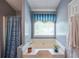Bathroom features soaking tub, window, and blue patterned shower curtain and valance at 1055 Kibbe Cir, Lawrenceville, GA 30044