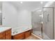 Primary bathroom featuring a soaking tub next to a glass shower enclosure, along with wood cabinets at 1717 N Decatur Ne Rd # 117, Atlanta, GA 30307