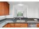 View of the kitchen sink and pass-through window into the living area with granite counters and wood cabinets at 1717 N Decatur Ne Rd # 117, Atlanta, GA 30307