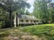 Inviting home showcases a classic design with a covered porch and dormer windows nestled within a wooded lot at 8291 Highway 5, Whitesburg, GA 30185