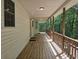 Long covered front porch with wood floors, and wooden railings surrounded by trees at 8291 Highway 5, Whitesburg, GA 30185