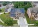 Aerial view showcasing a brick home with solar panels, a two-car garage, and a beautifully landscaped front yard at 893 Whitfield Oak Rd, Auburn, GA 30011
